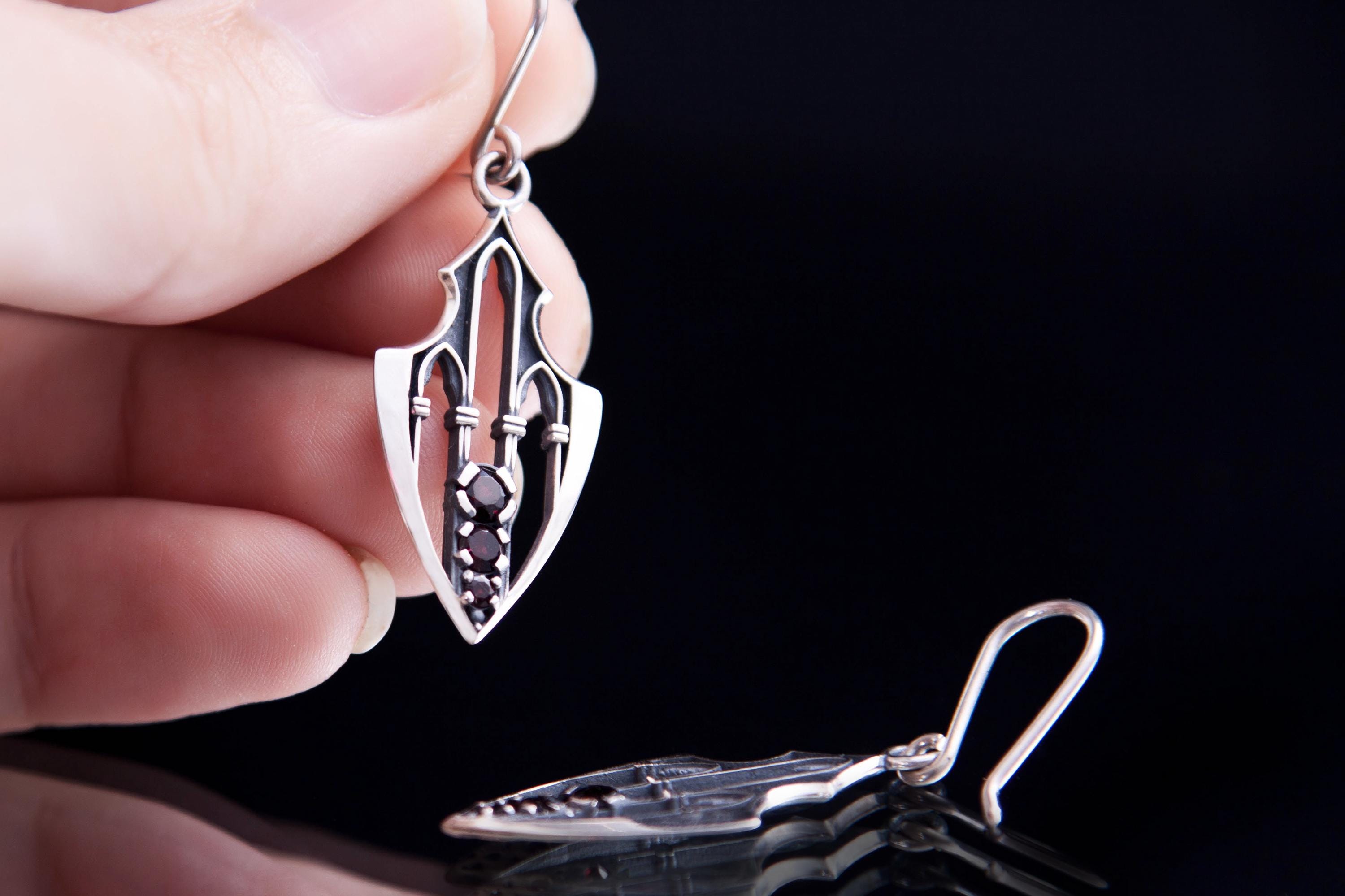 Long guardian earrings in silver with garnets held in hand