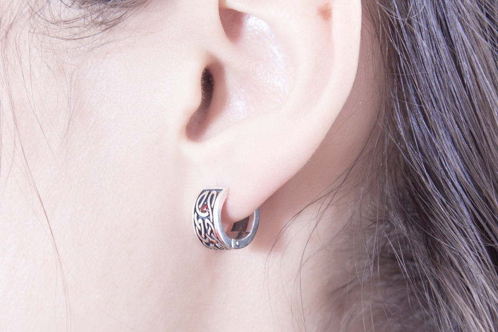 Celtic style silver huggie earring with detailed knot pattern on ear