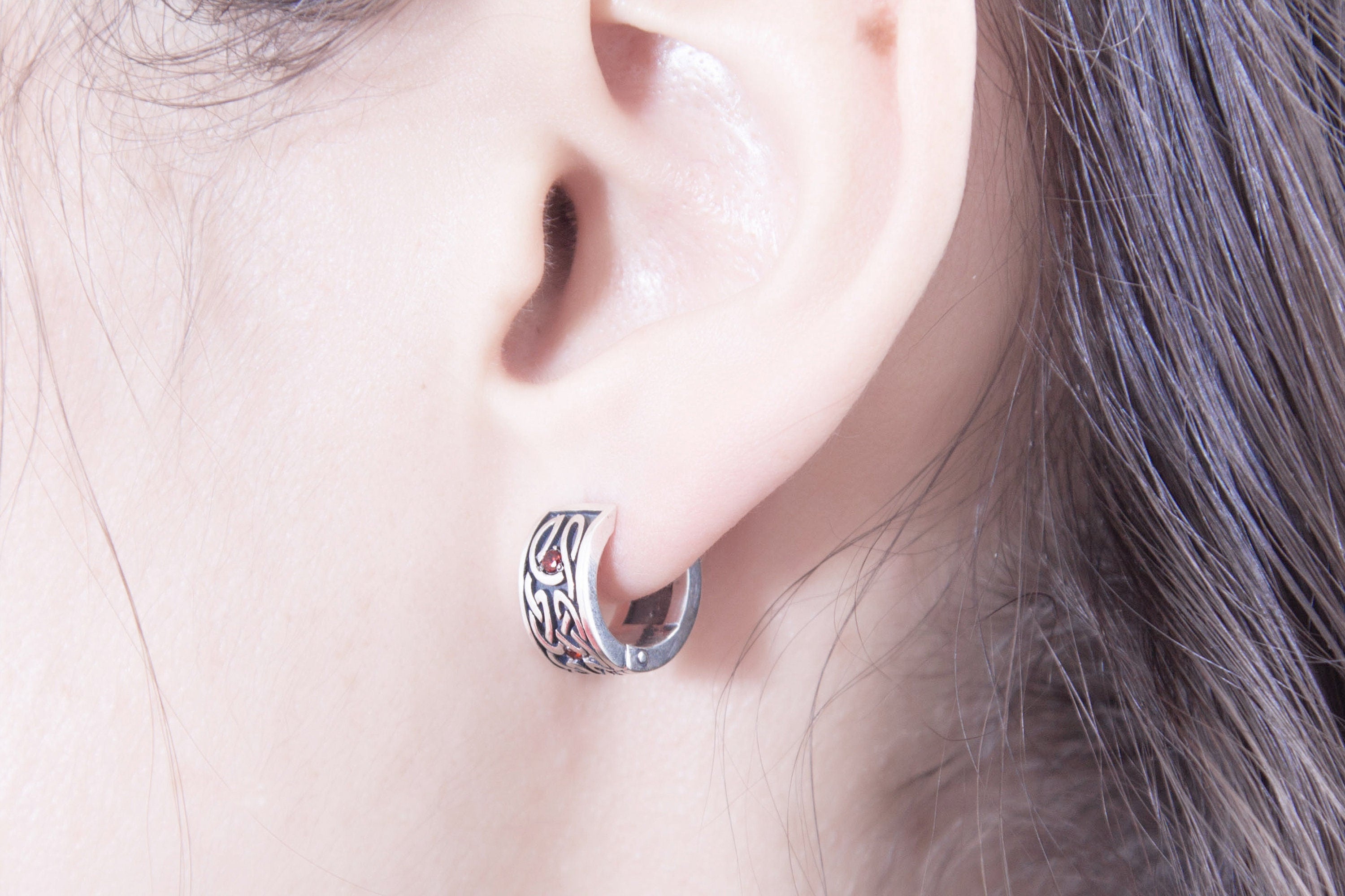 Celtic style silver huggie earring with detailed knot pattern on ear