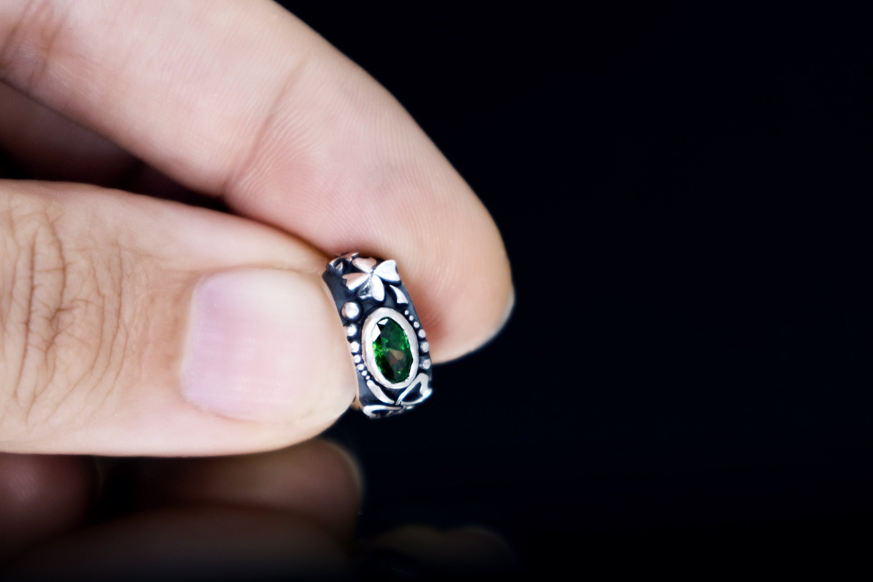 Silver clover ear cuff held between fingers, close-up detail