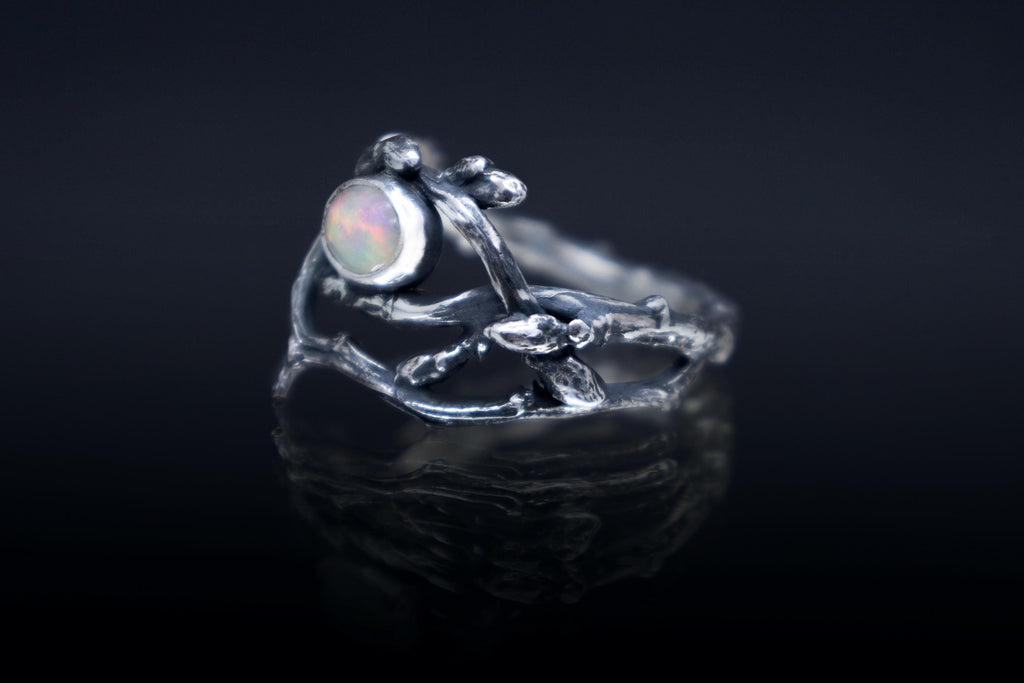 Sterling silver twig ring with natural Ethiopian opal on dark background