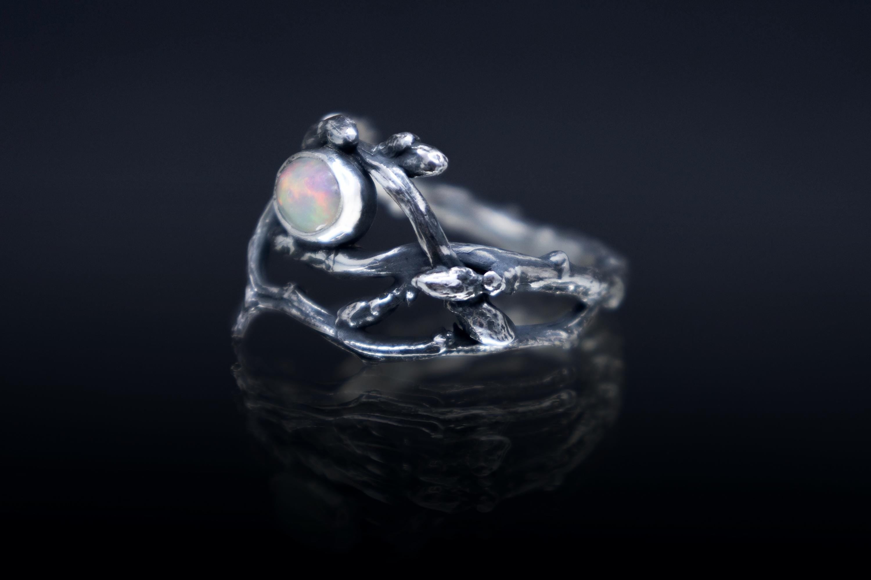 Sterling silver twig ring with natural Ethiopian opal on dark background