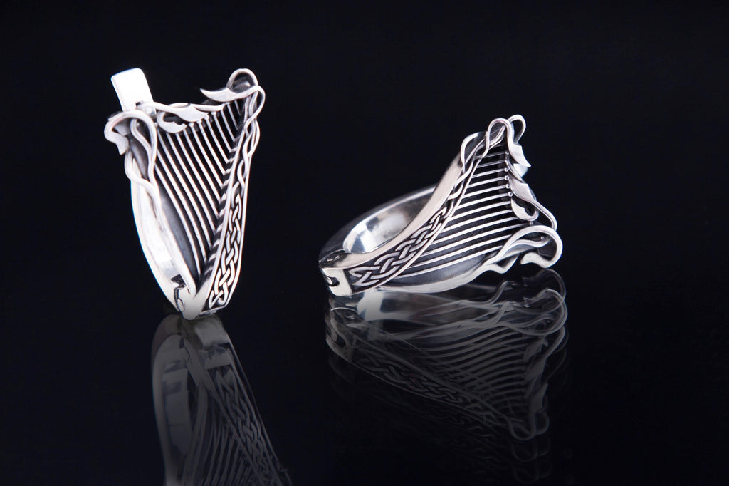 Close-up of harp-shaped silver earring with leaf details