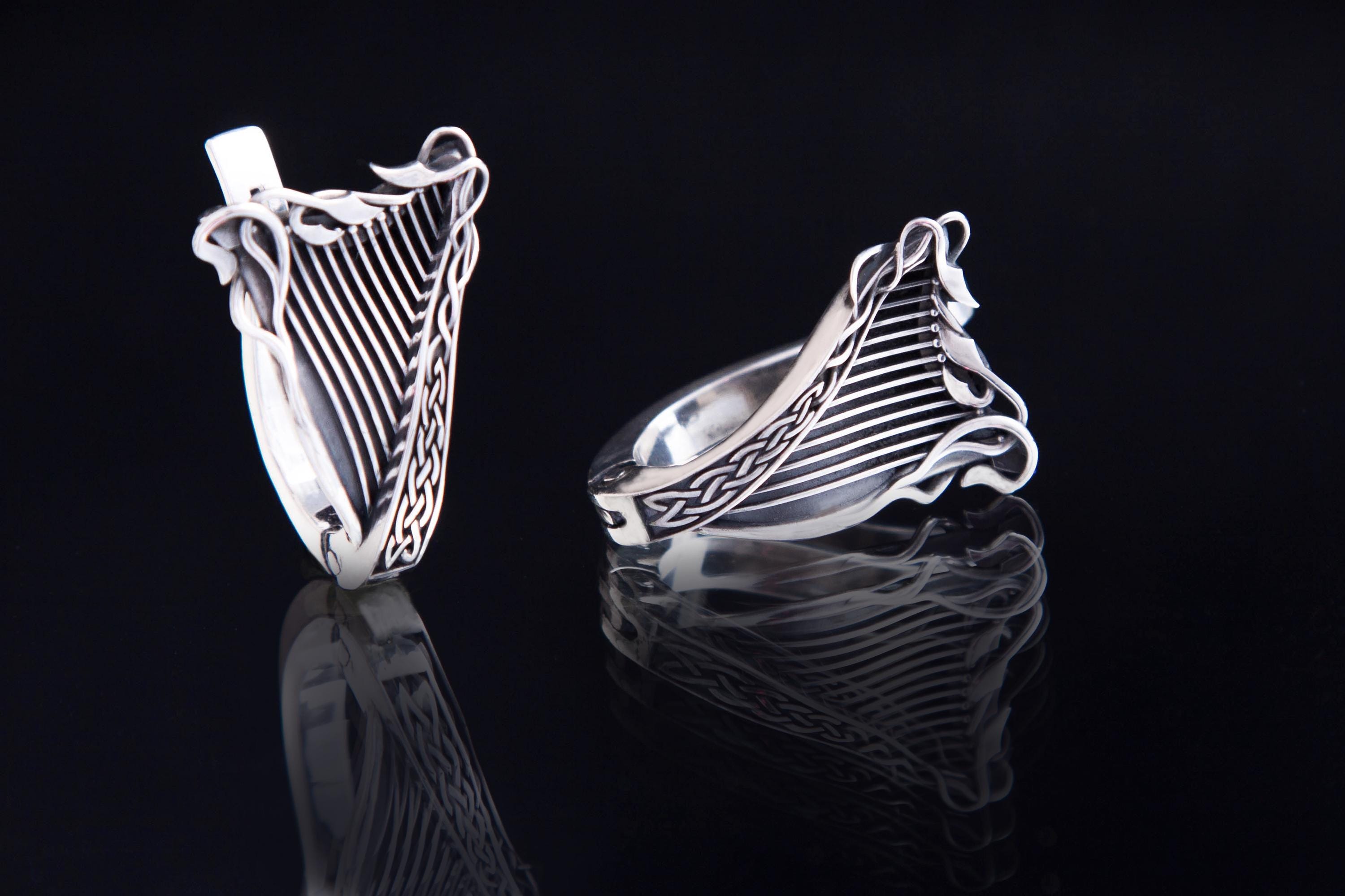 Close-up of harp-shaped silver earring with leaf details