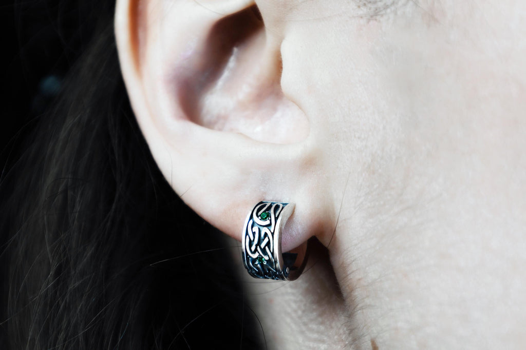 Celtic style silver hoop earring with detailed knot pattern on ear