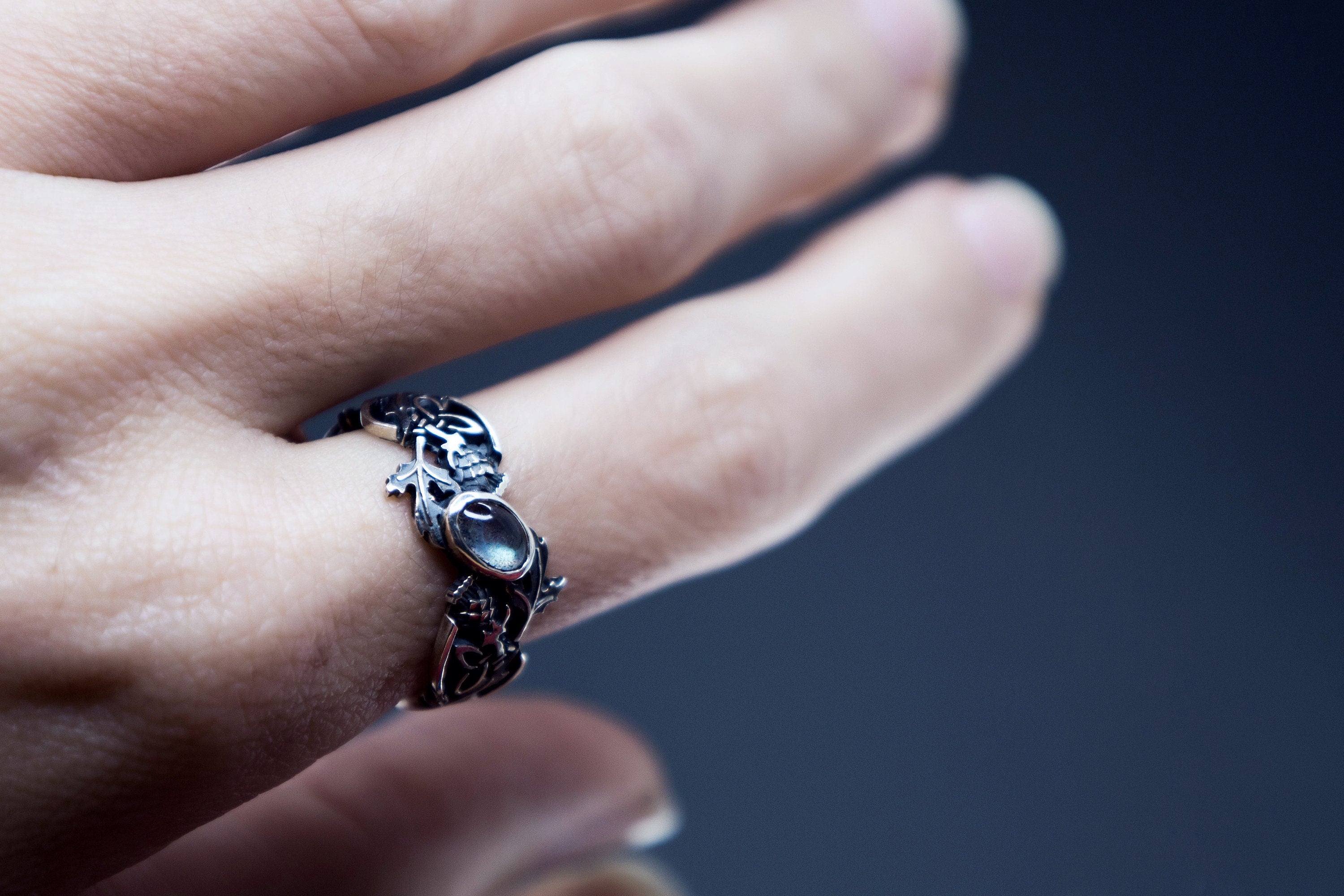 Hand wearing sterling silver thistle ring with natural labradorite