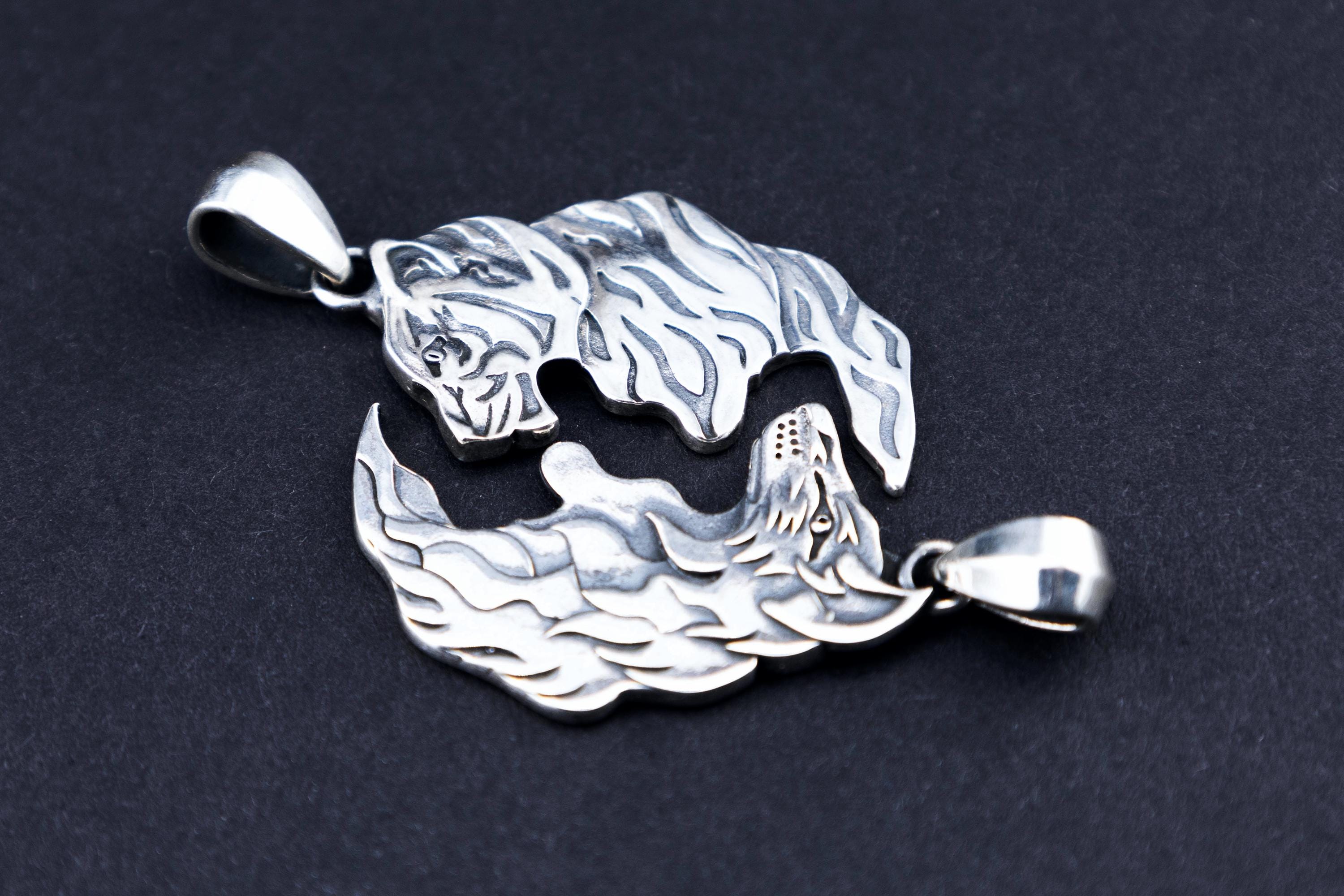 Sterling silver wolf and tiger matching pendants on black background