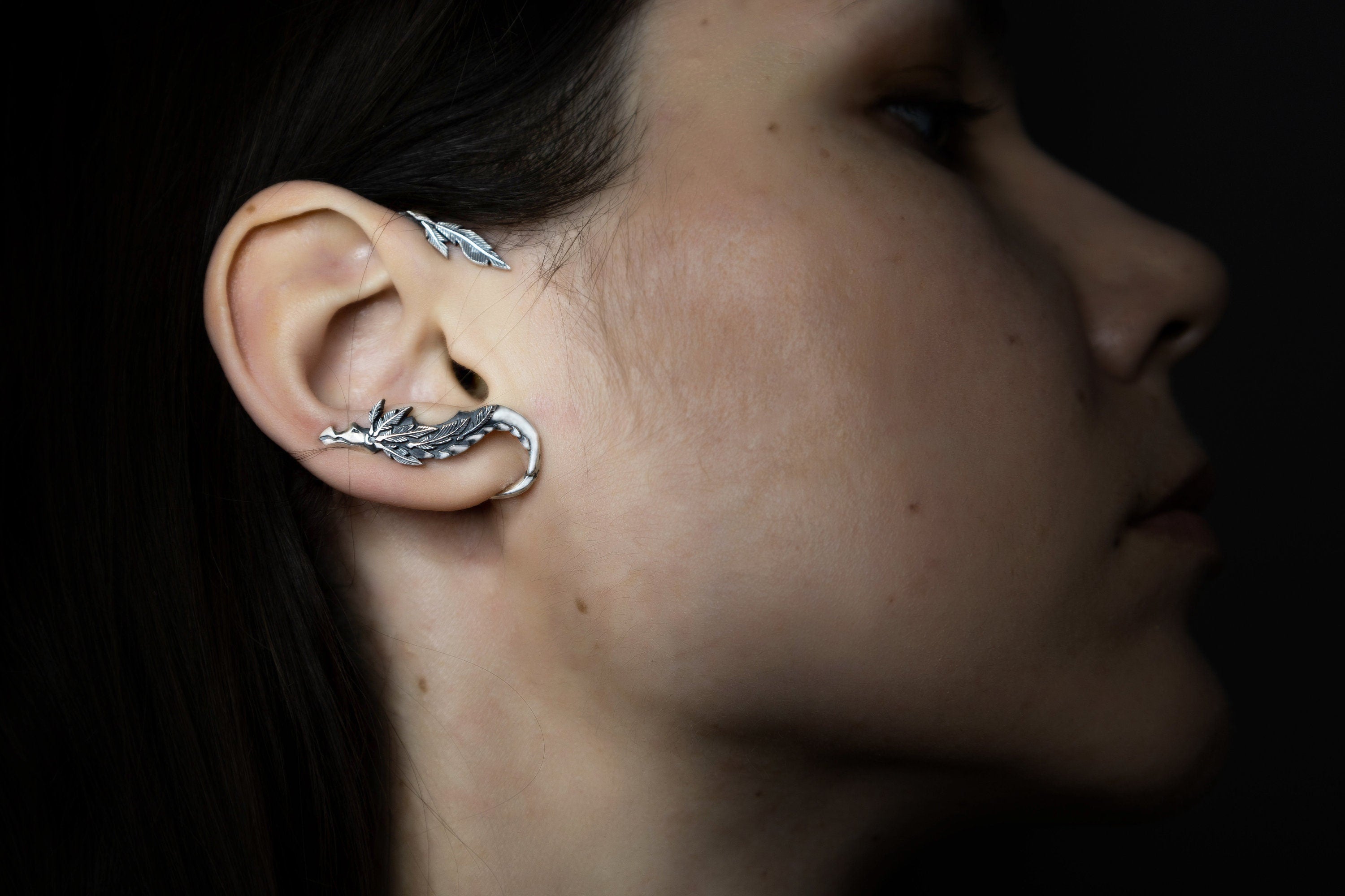 Side view of silver serpent ear wrap on ear, artisan jewelry