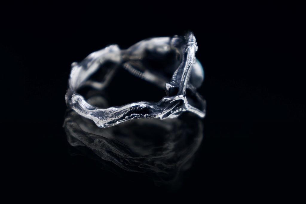 Side/back angle of sterling silver roots ring with branch texture, oxidized finish, black background studio photo.