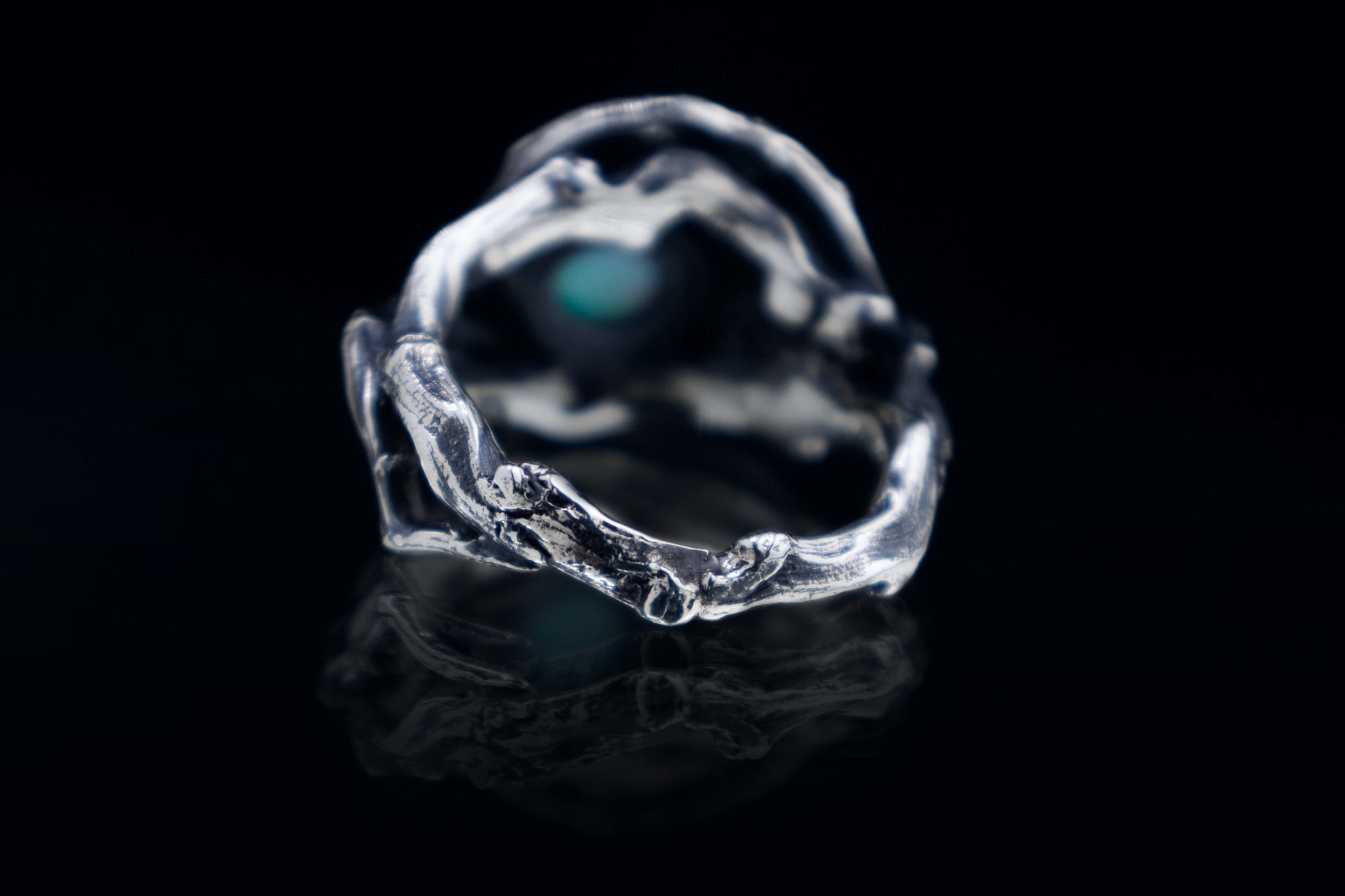 Side/back angle of sterling silver roots ring with branch texture, oxidized finish, black background studio photo.