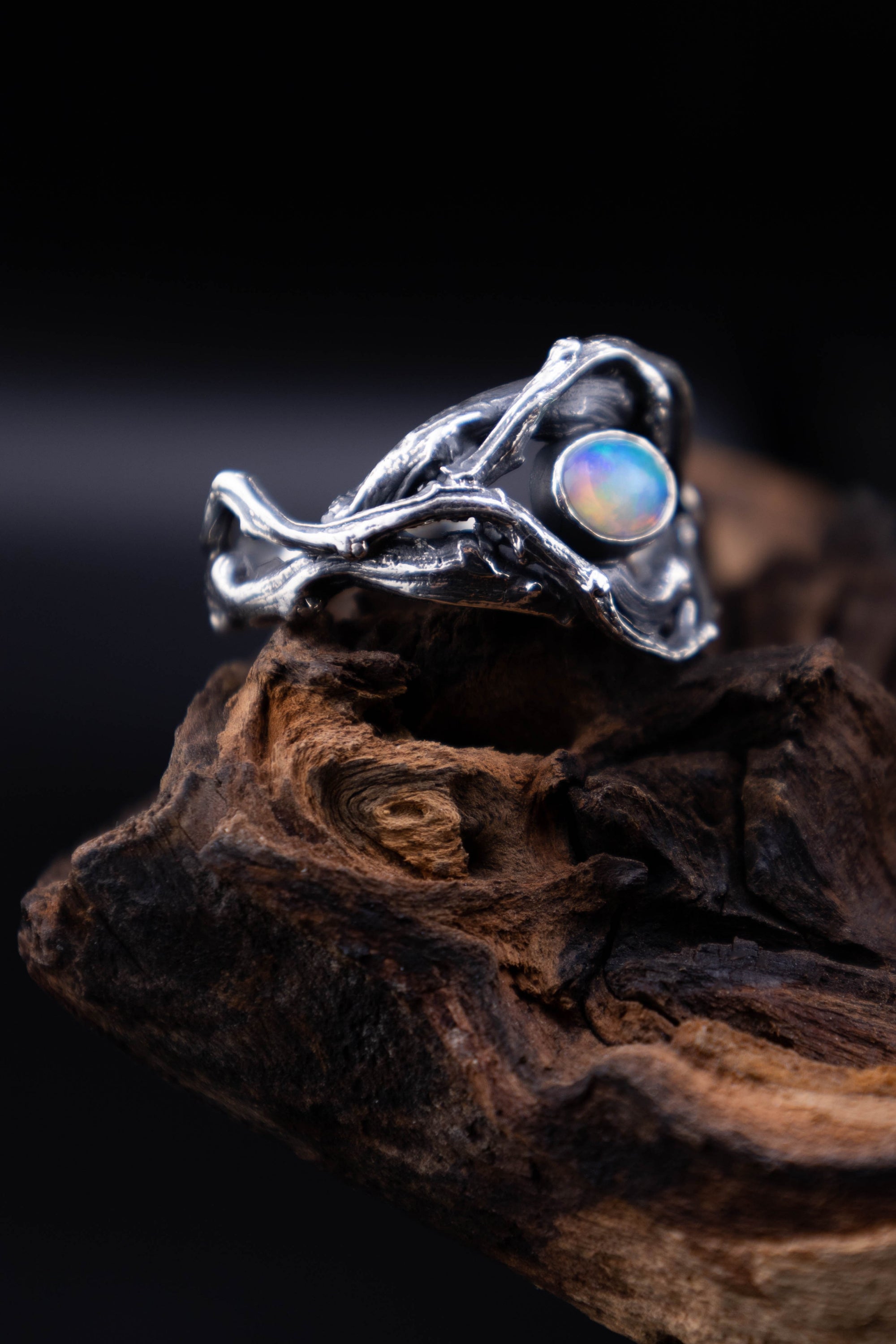 Oxidized sterling silver branch ring with natural Ethiopian opal on driftwood, side profile showing twisted twigs.