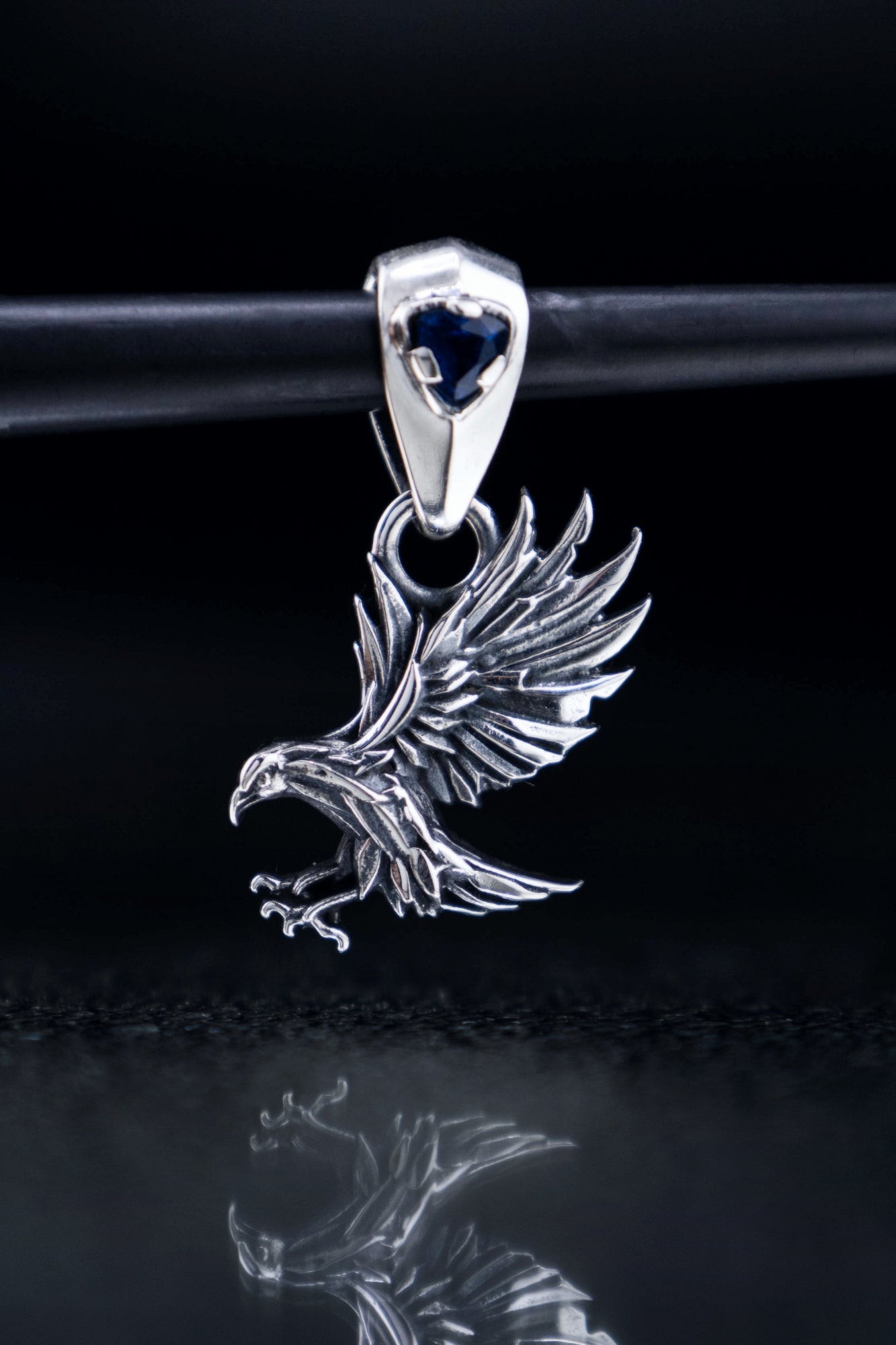 Handcrafted sterling silver raven pendant reflecting on black glass, gothic crow jewelry with blue gemstone, mystical bird artifact