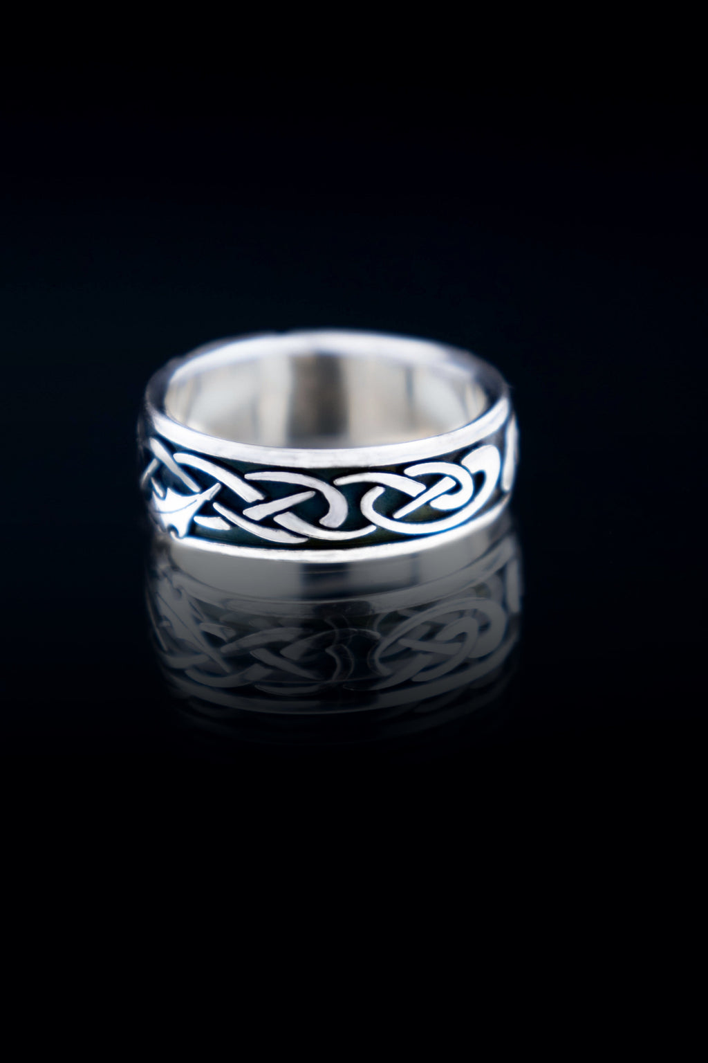 Silver ring with Celtic knot design on a black background