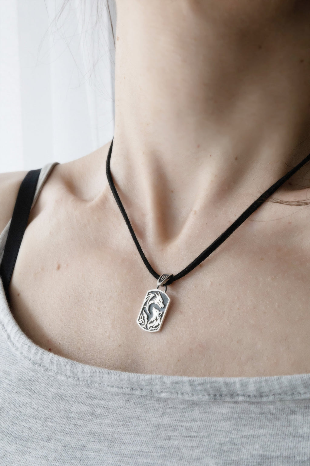 Dragon wolf silver pendant worn on collarbone on black cord, lifestyle jewelry shot, dark fantasy aesthetic