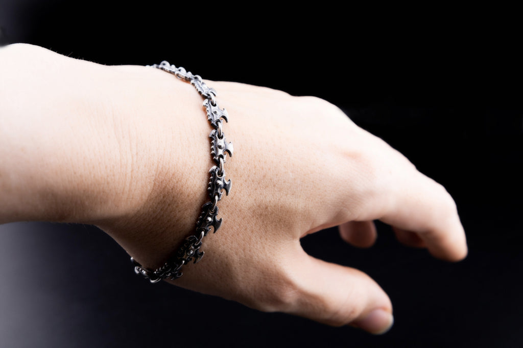 Oxidized sterling silver chainsaw bracelet worn on a hand, showing its close fit and repeating fantasy saw-blade links