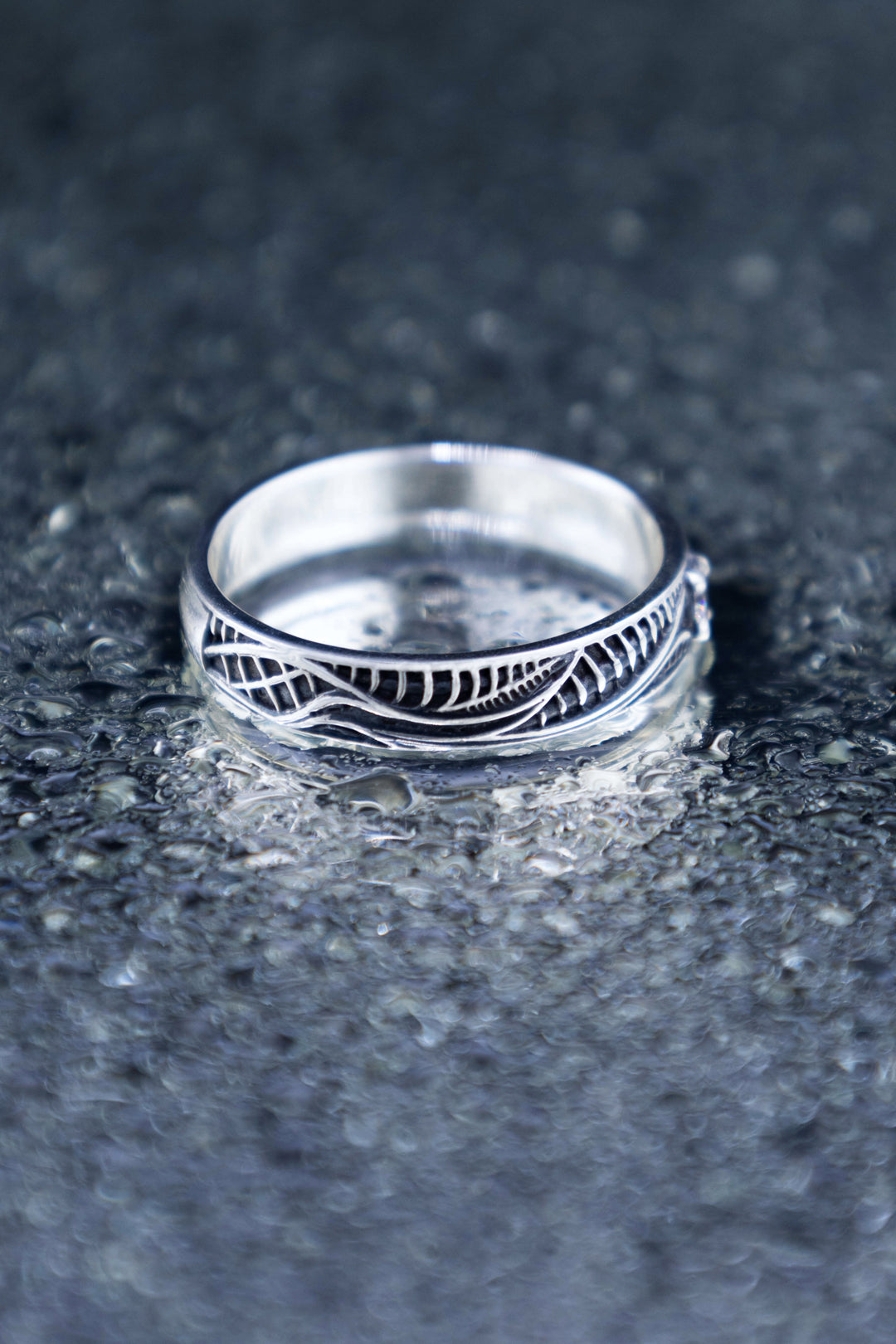Angled view of the biomechanical silver band, showing flowing lines, dark ribbed recesses and a smooth polished interior.
