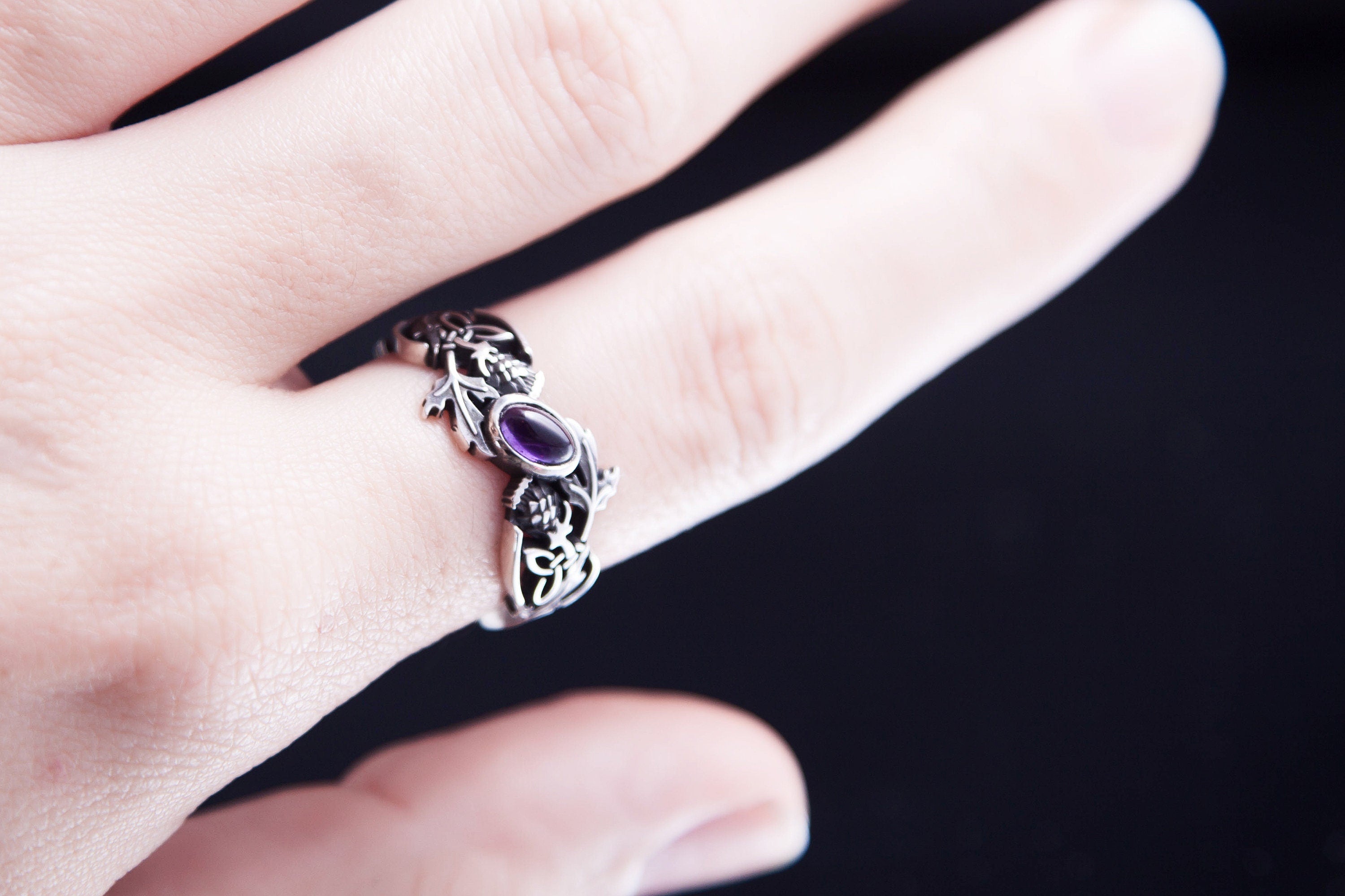 Hand wearing sterling silver thistle ring with natural amethyst
