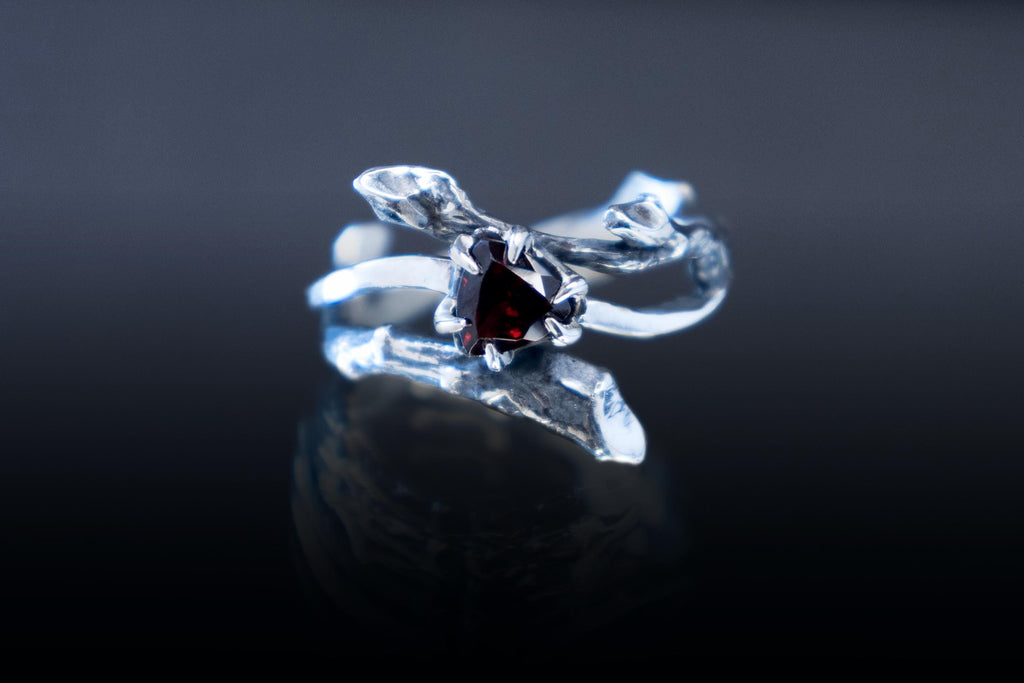 Elven silver twig ring with natural garnet on dark background