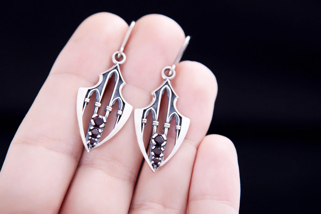 Long guardian earrings in silver with garnets held in hand
