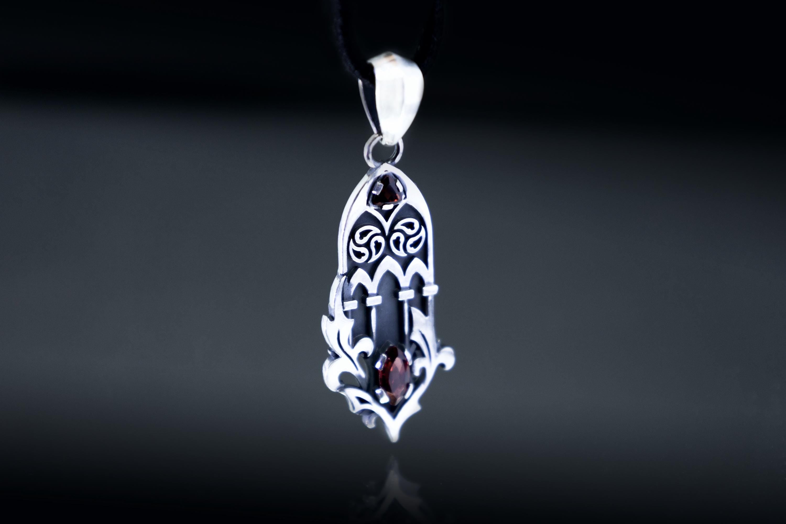 Openwork cathedral inspired silver pendant with garnet