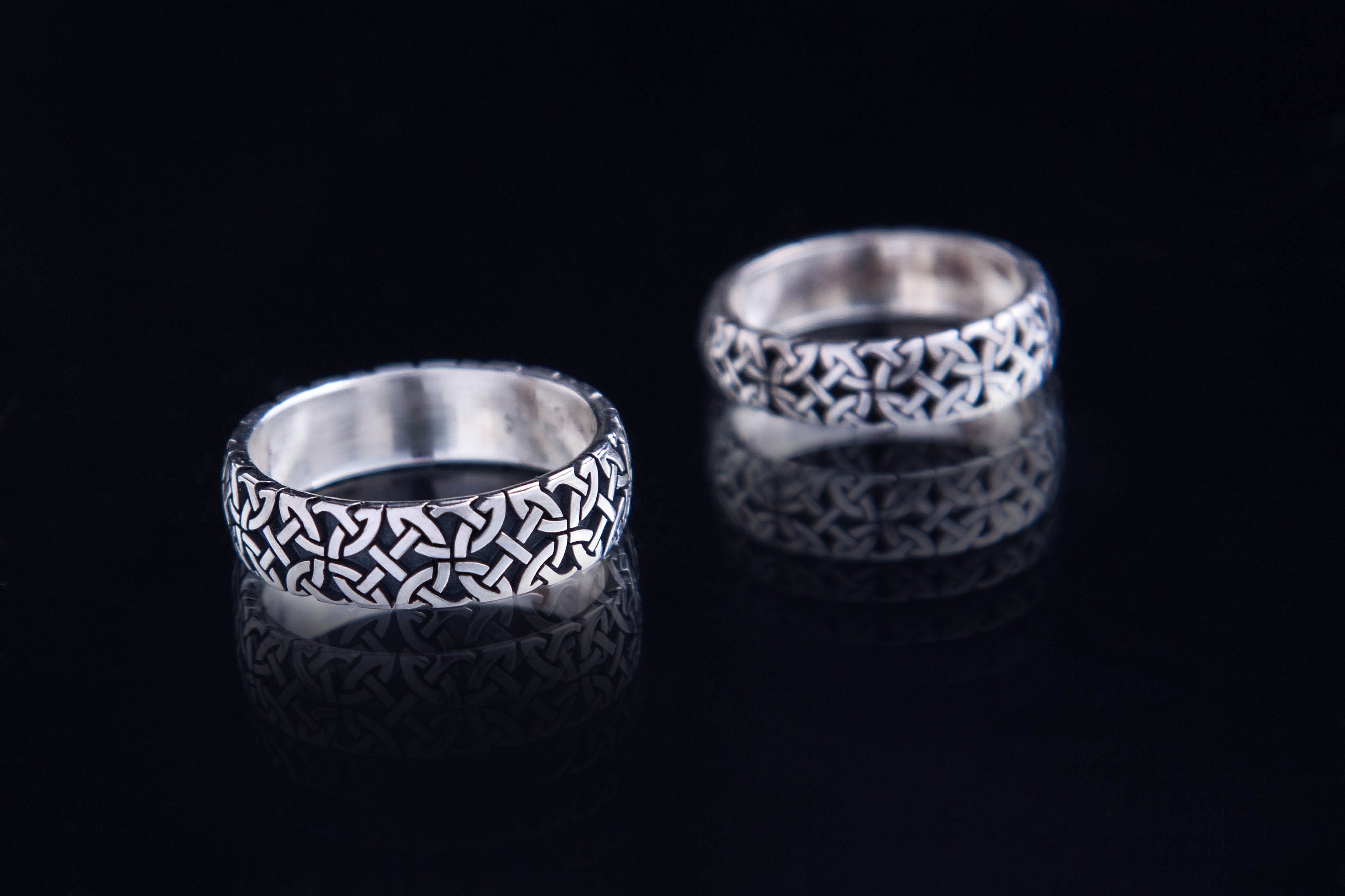 Wide sterling silver Celtic knot ring on dark background