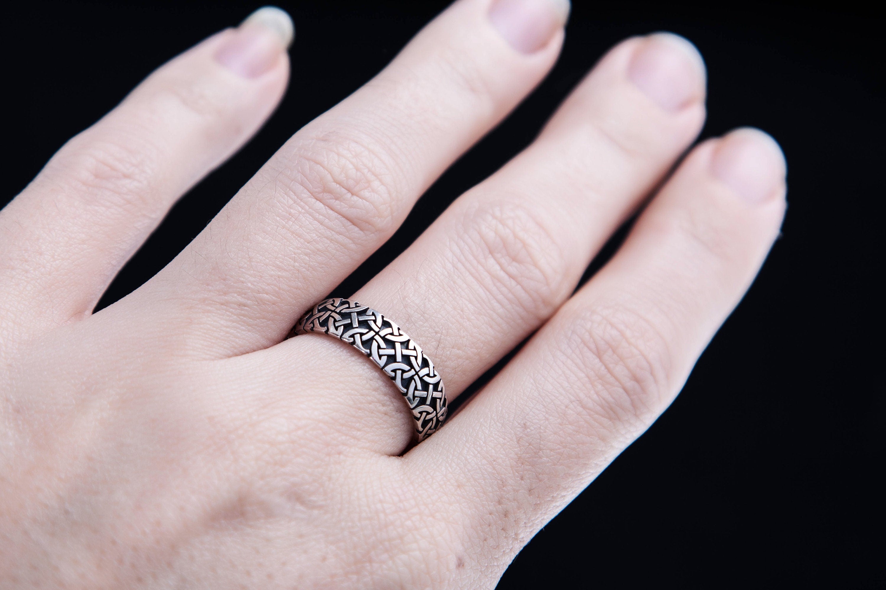 Hand wearing a wide Celtic silver ring